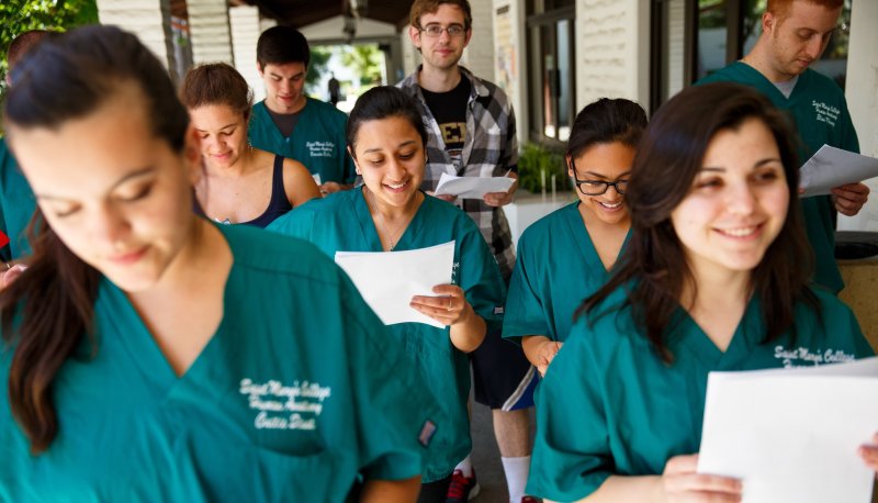 A group of Saint Mary's students wearing teal uniforms for Human Anatomy class and holding papers