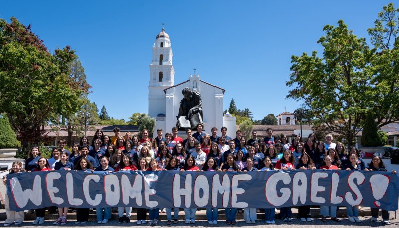 Students in front of Chapel with sign WELCOME HOME GAELS