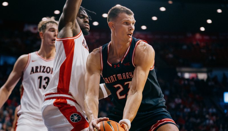 Men's Basketball player Paulius Murauskas holds the ball with defenders from Arizona in the background