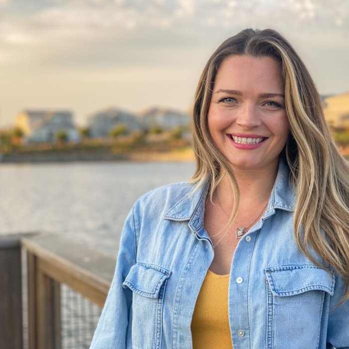 Mckenzie Langefeld looking at camera with her back to a waterfront