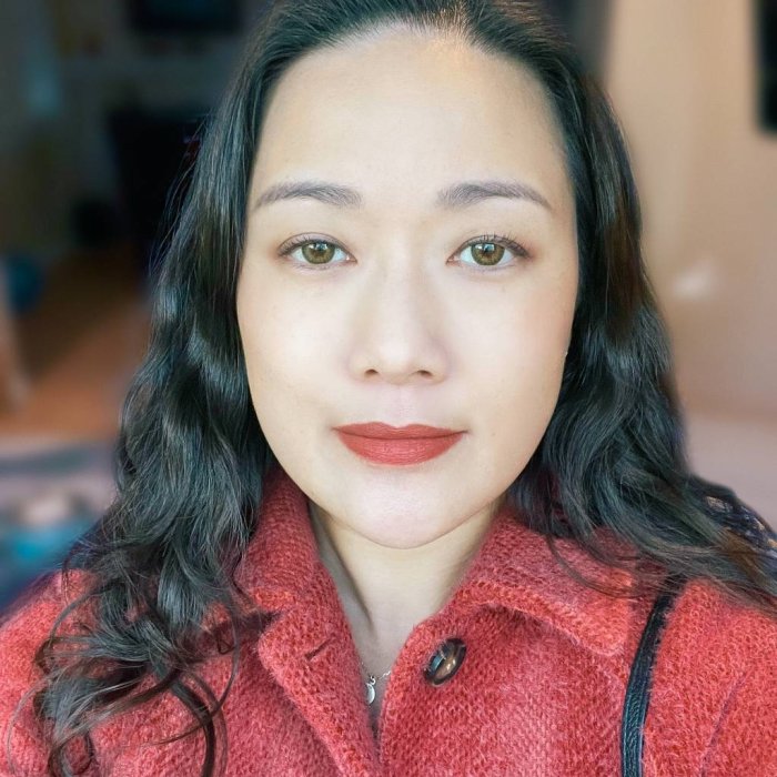 Headshot of Prof. Hilda Ma in red coat background is blurred