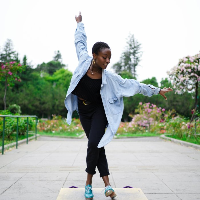 Micah Sallid in the middle of a dance pose outside in a garden.