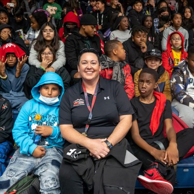 Lindsay Lopez-Wisely '04 sits amongst middle school students at a basketball game