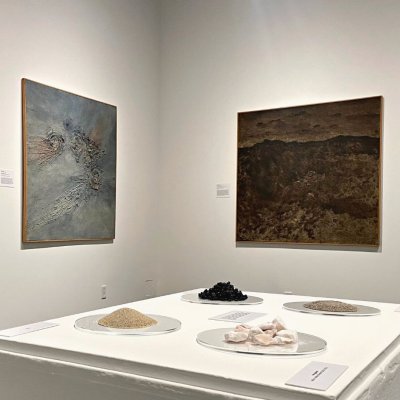 Installation image of From the Ground Up showing paintings and earth materials of asphalt, gypsum and sand.