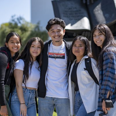Five Saint Mary's students in front of statue of John Baptist de la Salle