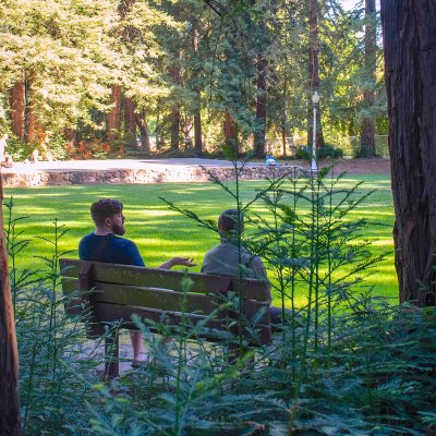 Two participants in 2023 Lasallian DEIB workshop seated on bench in in redwood grove