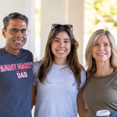 A student and her parents smile for a photo during Family Weekend
