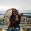 a woman is sitting down outside and smiling with an ice cream cone