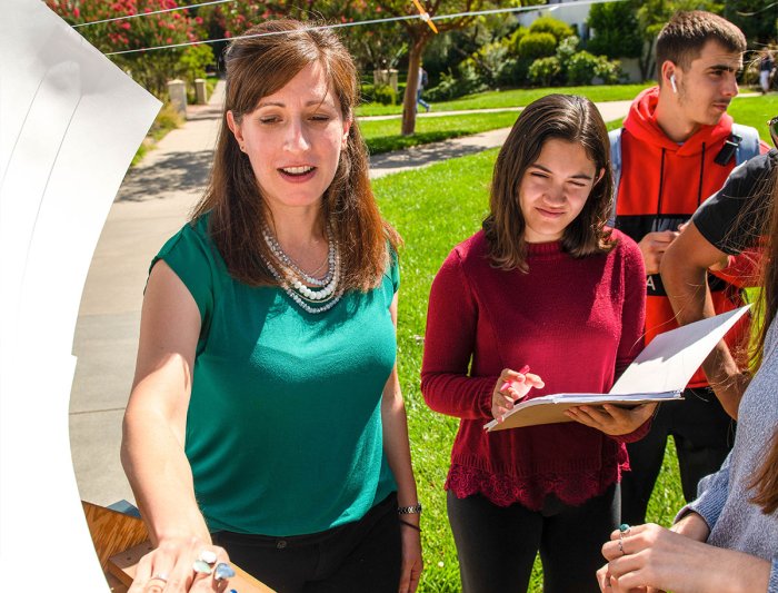 student and teacher examine object during outdoor class