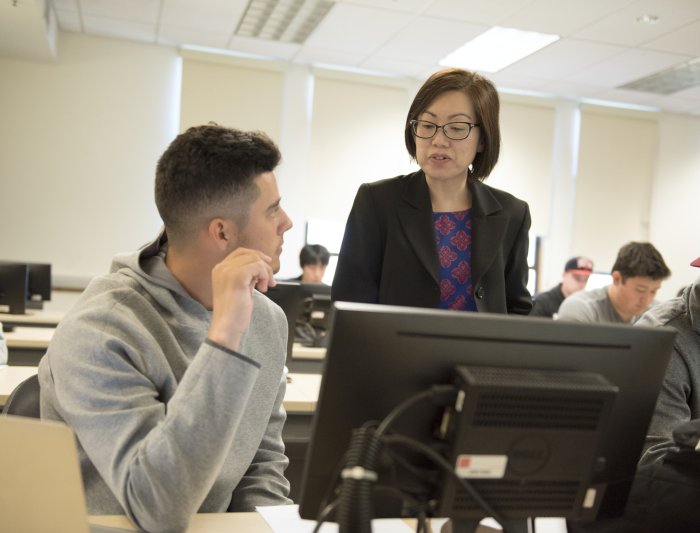 A professor talking to a student at a desk