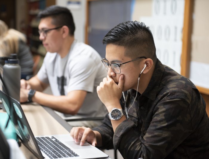A student studying in the library with headphone on