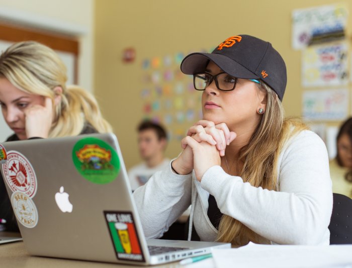 A student has her laptop open in front of her while she is listening to the professor