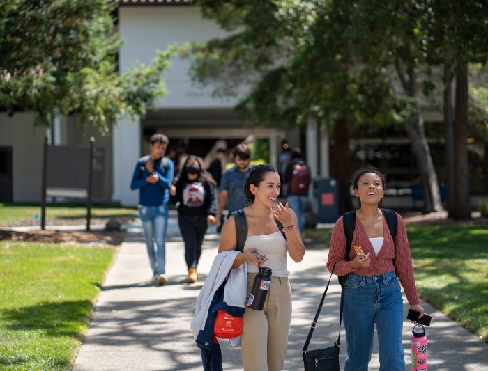 two students are walking through campus as they're chatting