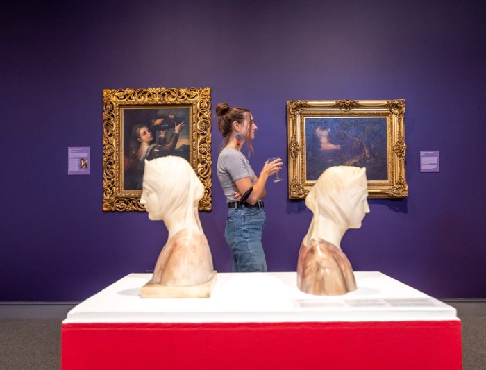 A student standing between two busts at the museum of art