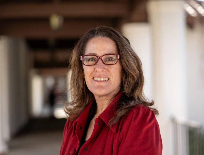 Headshot of Julie Scaff, brown medium length hair wearing a red jacket and red glasses