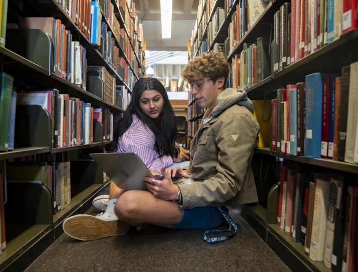 Students sitting in between rows of books studying