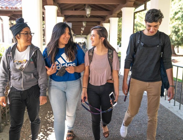 four students walking in outside hallway