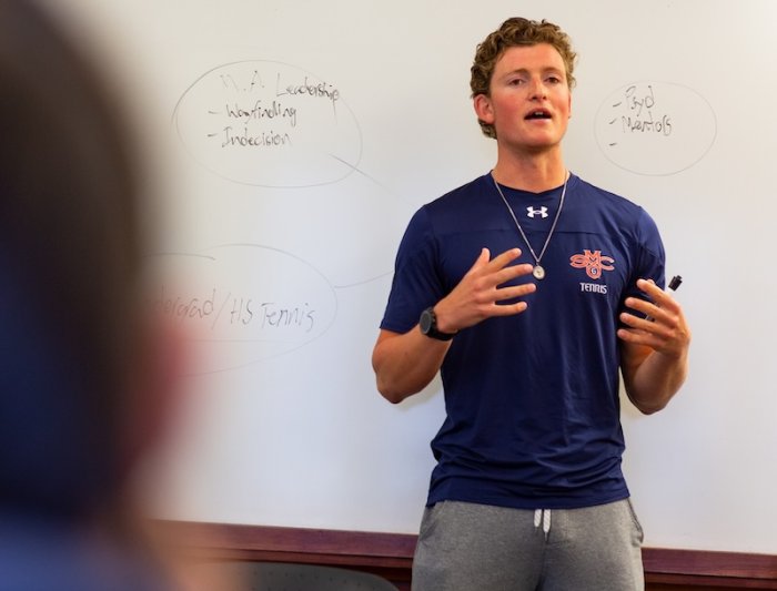 SMC Men's Tennis player in front of white board in class on leadership