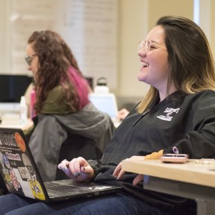 Woman laughs while using her computer in a classroom