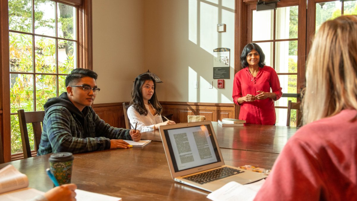 Two students and a professor discuss a text during class