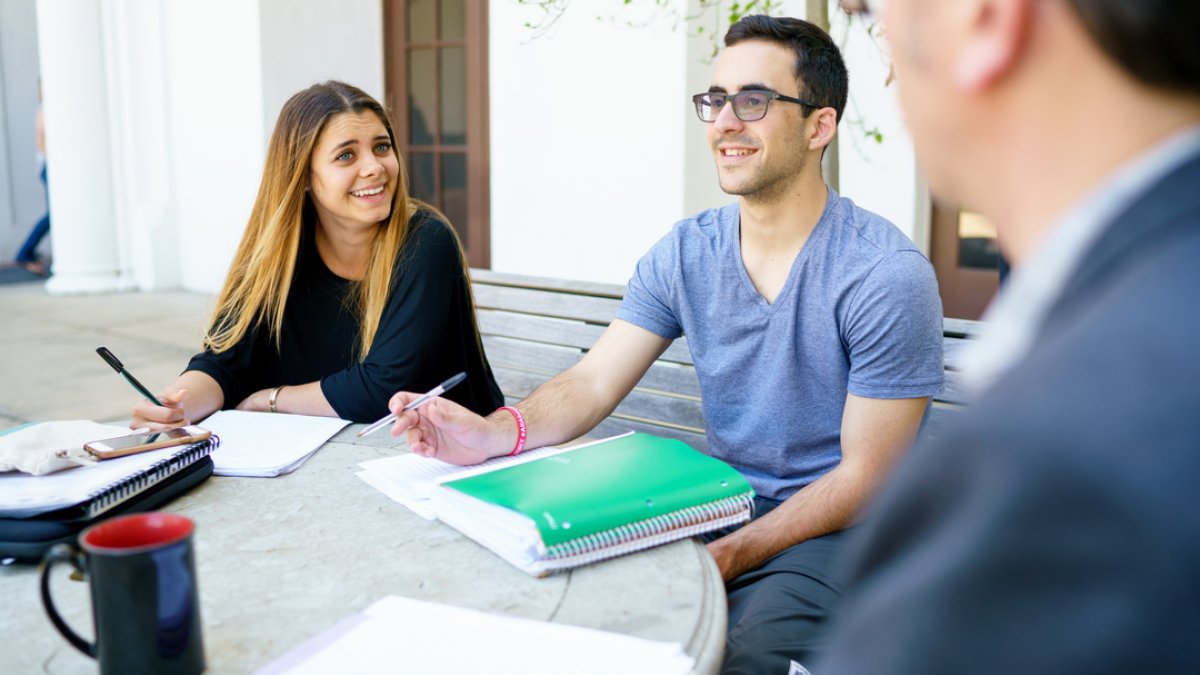 Student at the writing center meeting at a table outside on Saint Mary's campus