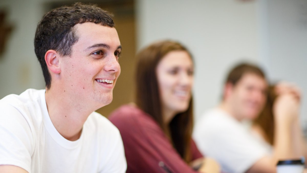 Students are sitting at their desks in class looking up and smiling