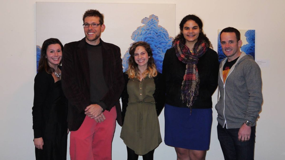 5 people standing side by side in-front of a large painting