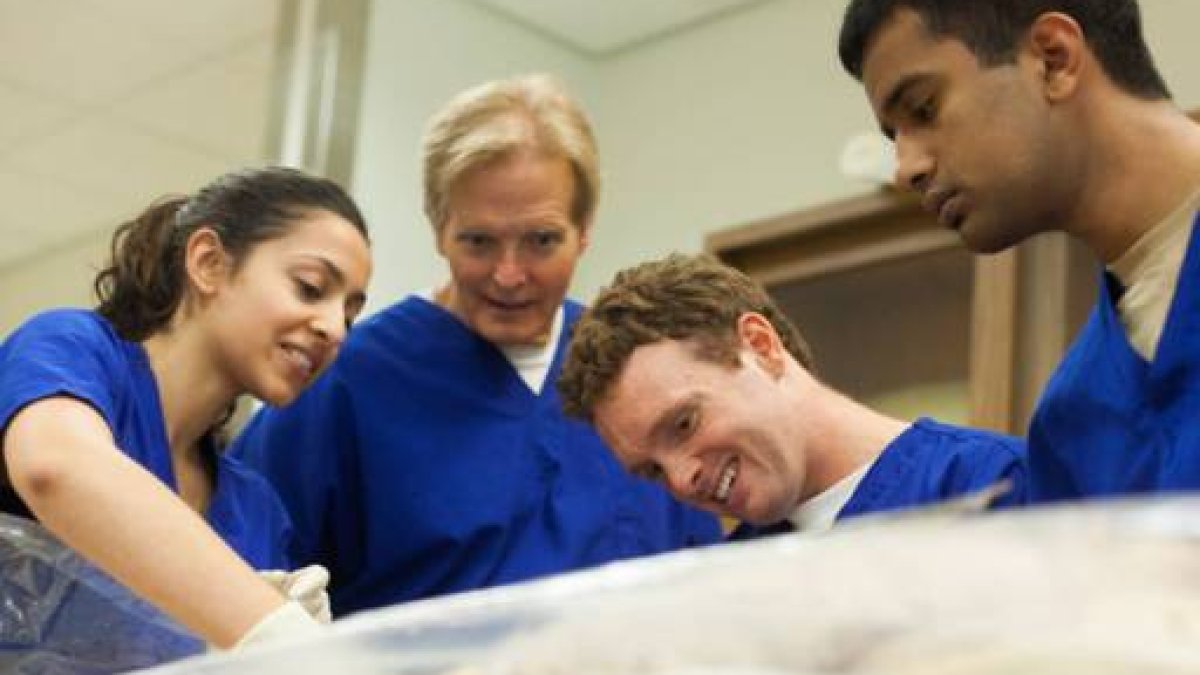 three students and professor wearing scrubs in classroom