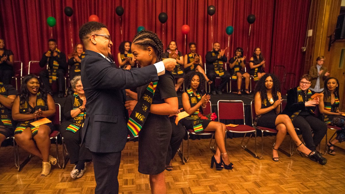 A student at black graduation having a stole put over her head