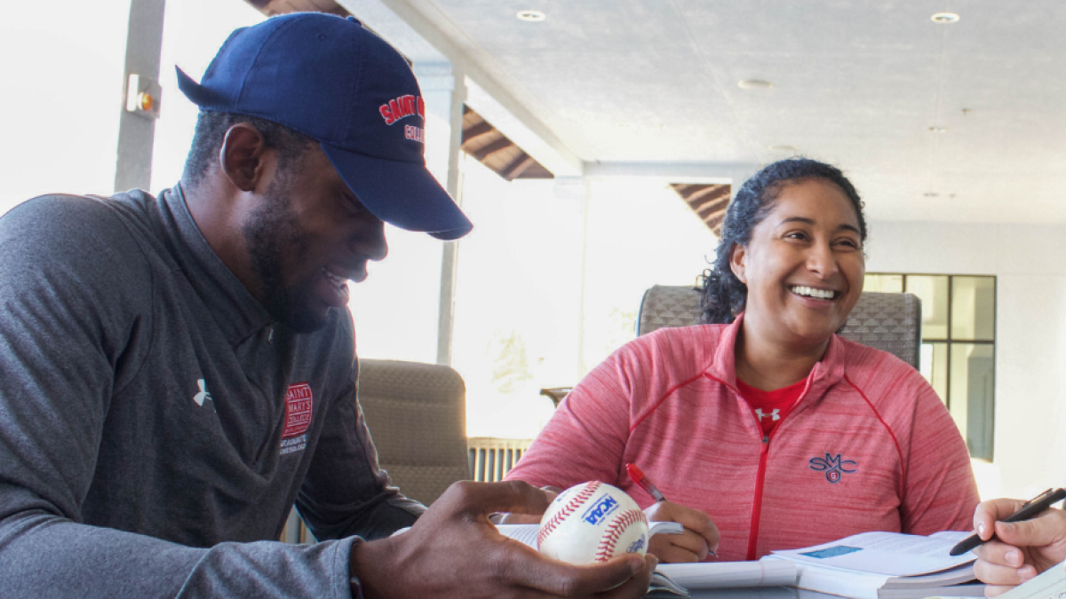 Students studying, one holding a baseball.
