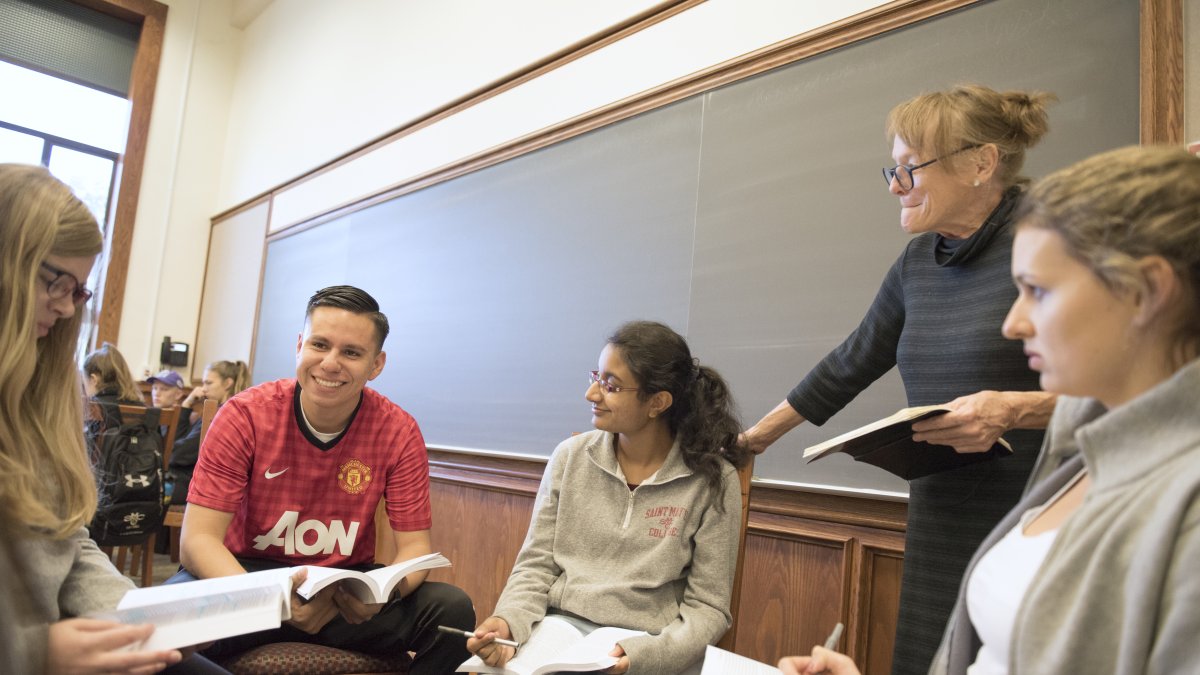 A professor listening to a group of students in the middle of a discussion