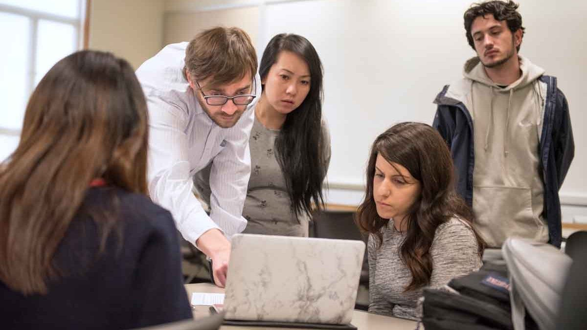 A professor demonstrating to a group of student with a computer