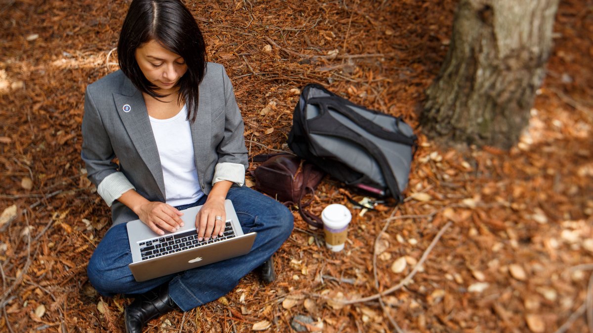 A student writes in the redwood grove.