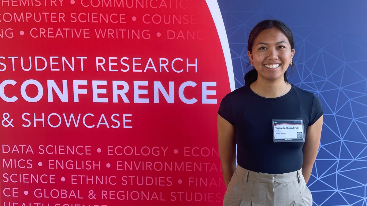 Student standing in front of the Student Research Conference backdrop