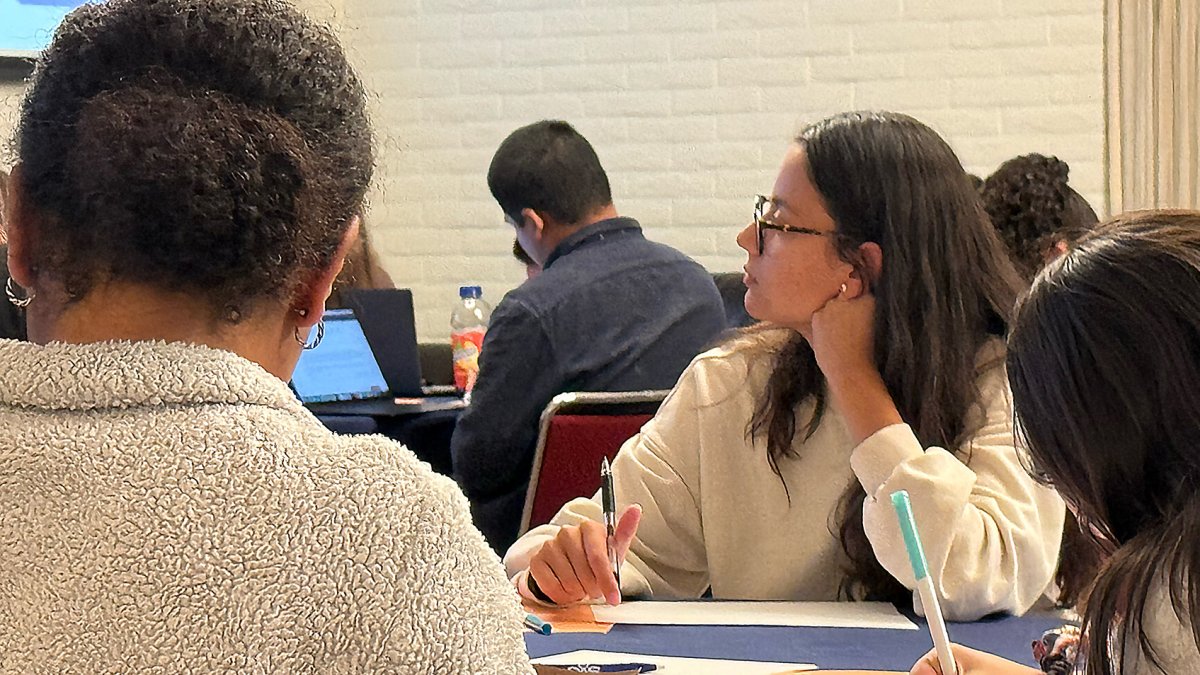 Students in Claeys Lounge watching a presentation and writing