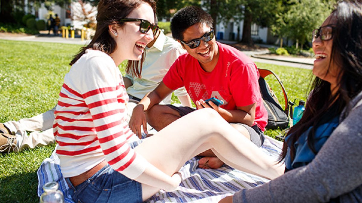 Students laughing sitting on the lawn