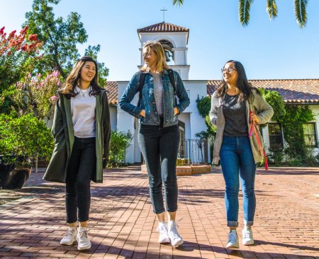 three students walking on brick walkway on sunny day